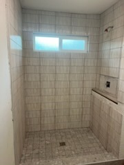 Light gray vertical subway tile shower with transom window and glass door by Level 4 Tile and Stone San Diego