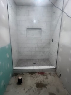 White large format subway tile shower with single wide recessed niche under construction by Level 4 Tile and Stone San Diego