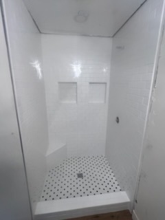 Clean white subway tile shower with dual niches and penny round floor by Level 4 Tile and Stone