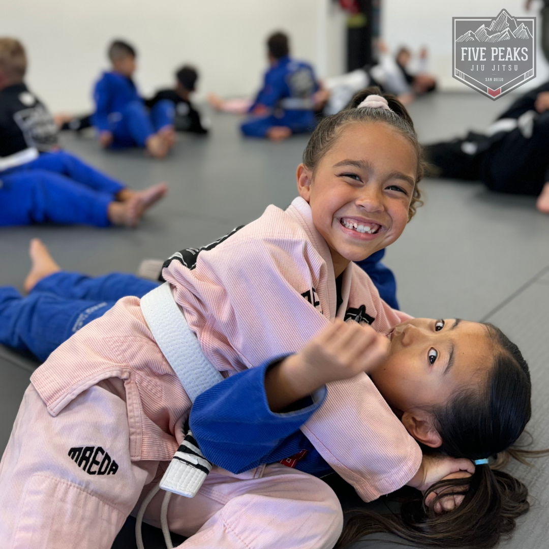 Two girls smiling while training jiu jitsu together at Five Peaks Jiu Jitsu