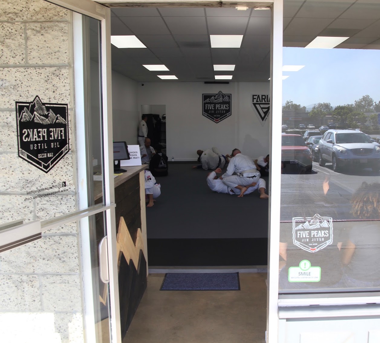 Front entrance of Five Peaks Jiu Jitsu academy in Tierrasanta showing students training on the mat