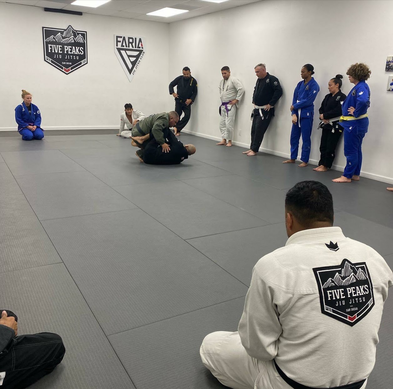 Students and instructors gathered around the mat at Five Peaks Jiu Jitsu