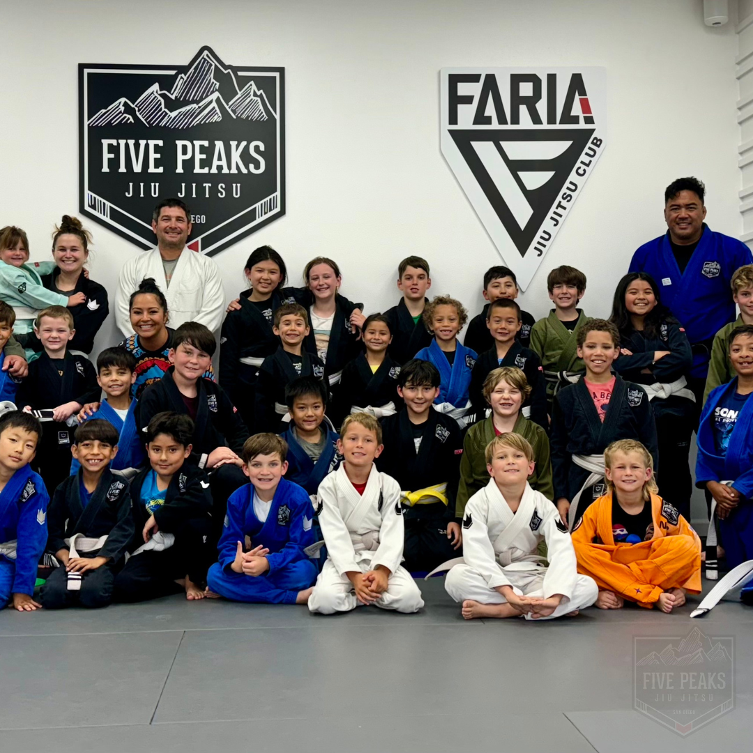 Kids and coaches posing together on the mat at Five Peaks Jiu Jitsu academy in Tierrasanta, San Diego