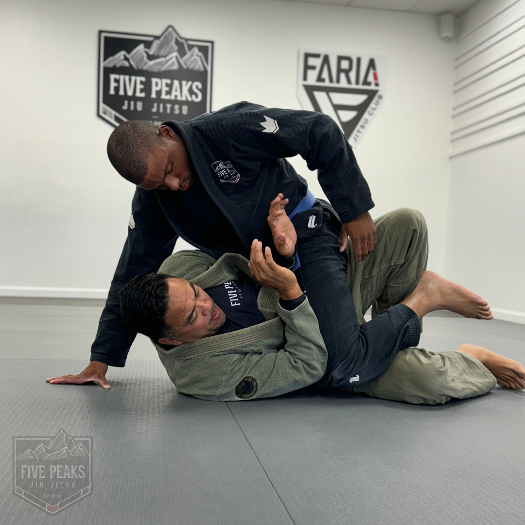 Adult students grappling on the mat with Five Peaks and Faria Jiu Jitsu Club logos on the wall