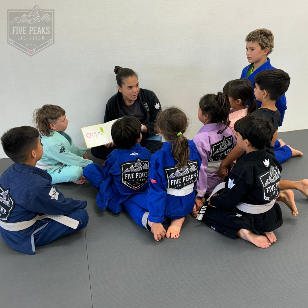 Coach reading to a group of kids seated on the mat at Five Peaks Jiu Jitsu