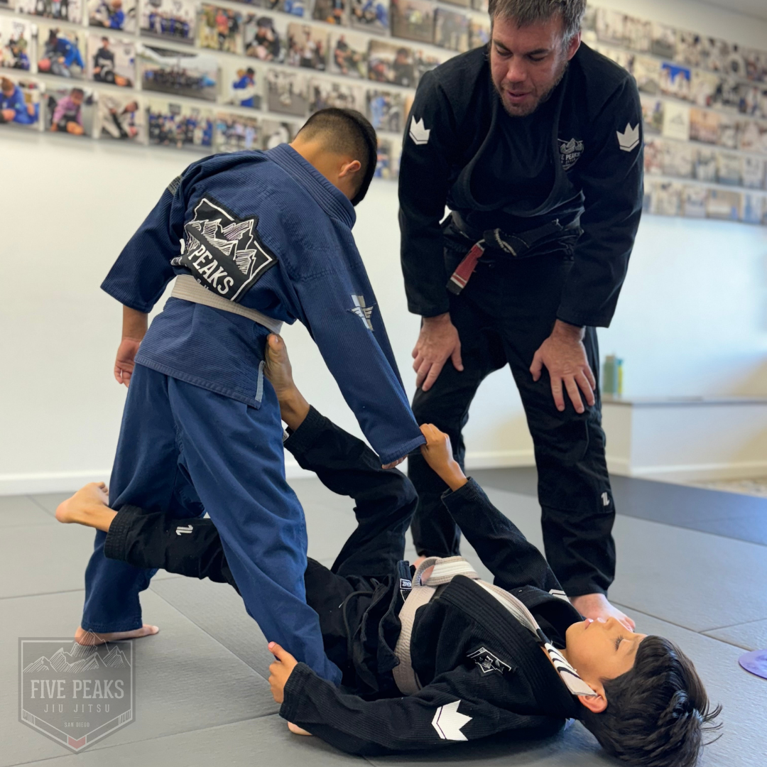 Instructor overseeing technique practice on the mat at Five Peaks Jiu Jitsu