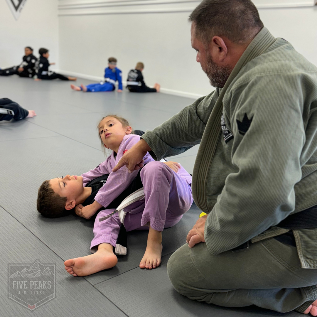 Coach guiding young students through ground positions and technique on the mats