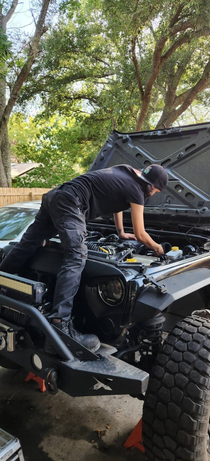 Technician inspecting an open Jeep engine bay at Danny Auto Repair in Hudson, Florida.