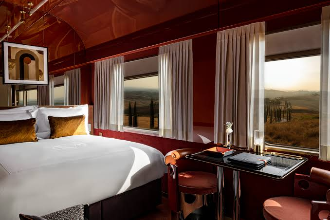 A private Orient Express cabin suite with warm brass tones overlooking the Tuscan countryside