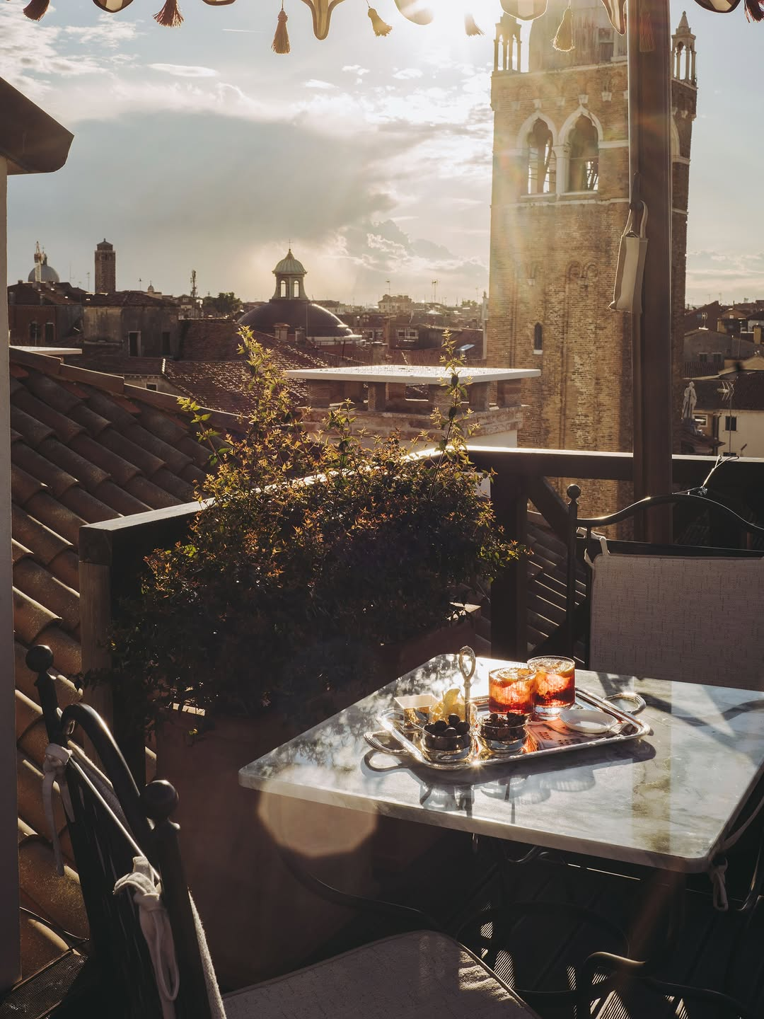 Orient Express luxury hotel terrace overlooking historic Venetian rooftops at golden hour