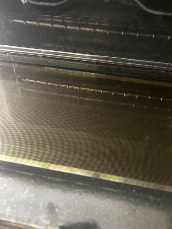 Before cleaning: Baked-on grease and dark residue clouding the oven door glass window