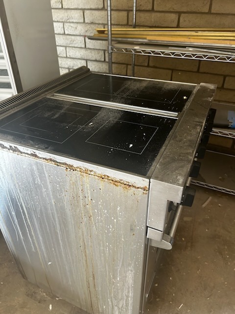 Before cleaning: Electric range with heavy splatter residue, side rust stains, and dull cooktop glass