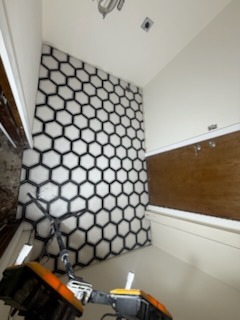 Hexagon mosaic tile accent wall installation in vaulted hallway with wood trim details