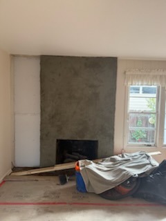 Smooth grey plaster fireplace surround under construction with drywall prep