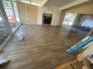Extensive wood-look plank tile floor installation across open living space with fireplace