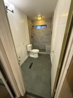 Remodeled bathroom suite with custom walk-in shower, bench, and green hexagonal floor tile