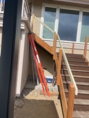 Custom exterior wood stair railing installation next to home entrance under construction