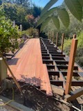 Elevated wooden walkway and staircase construction on a hillside garden path