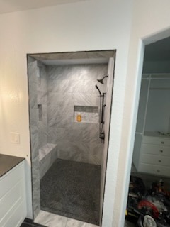 Fully tiled walk-in shower with built-in bench, recessed niche, and handheld shower head