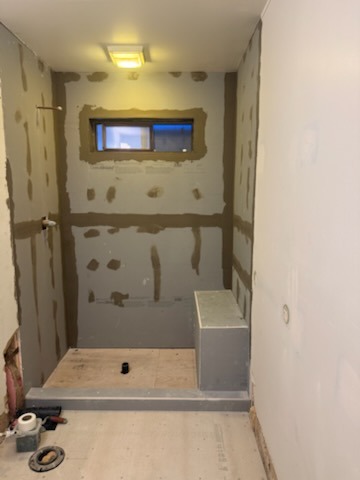 Cement backer board installation and joint taping with mud across full shower enclosure with built-in bench and window sill