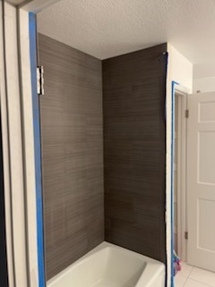 Modern dark linear shower tile surround installation over bathtub