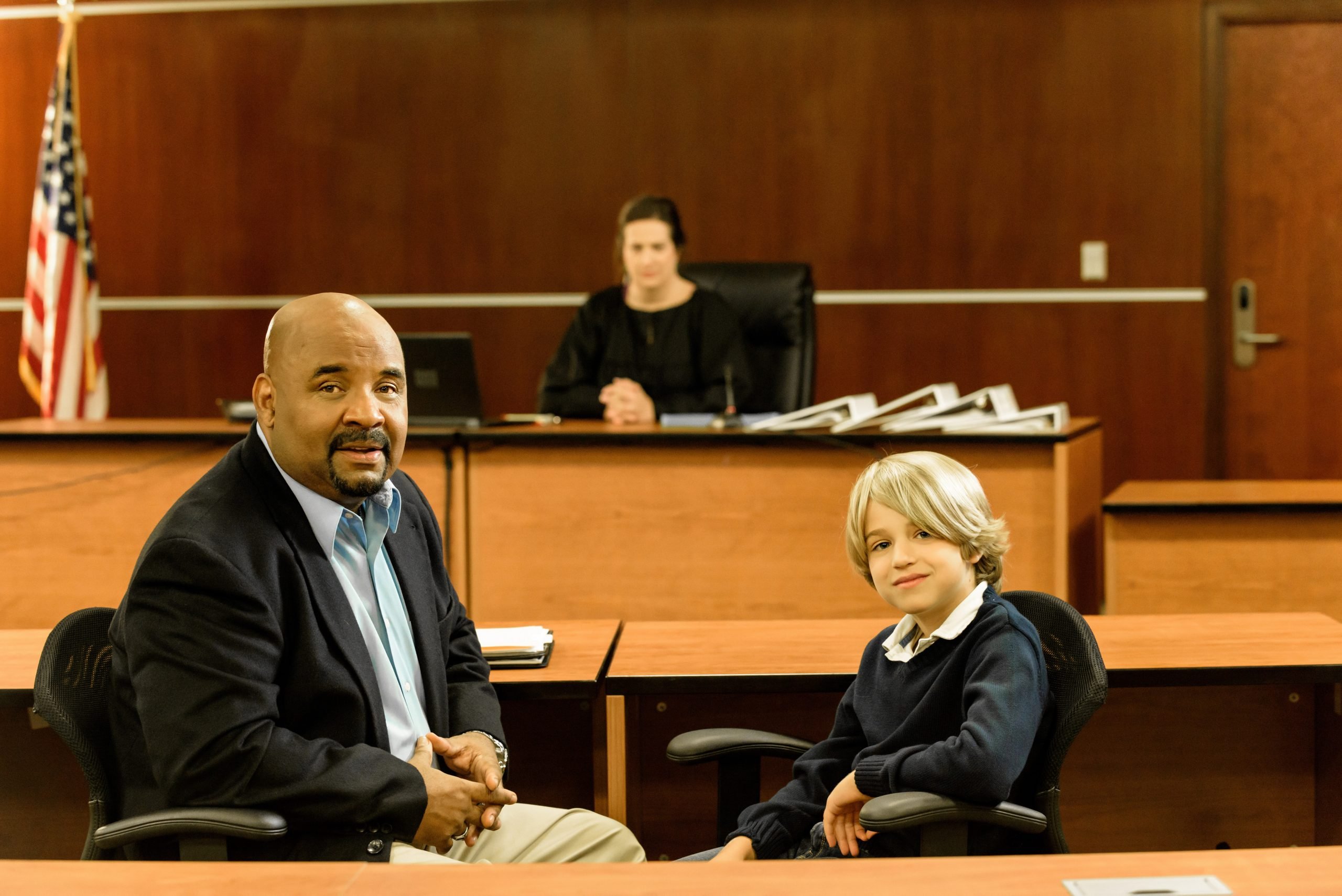 An adult and child seated together in a courtroom.