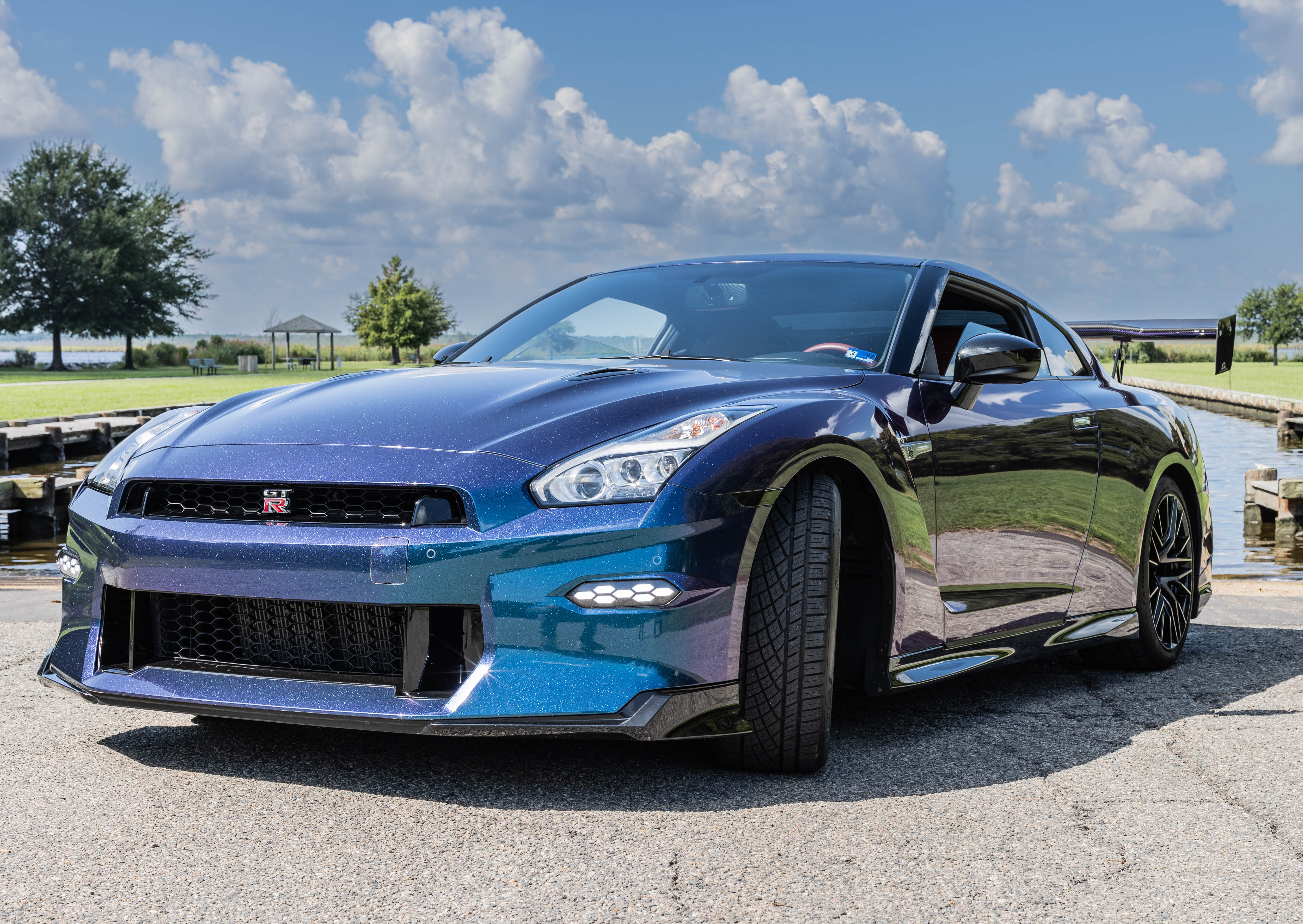 2024 Nissan GT-R Premium front quarter panel showing metal-flake purple-to-blue color-shift paint under bright sky