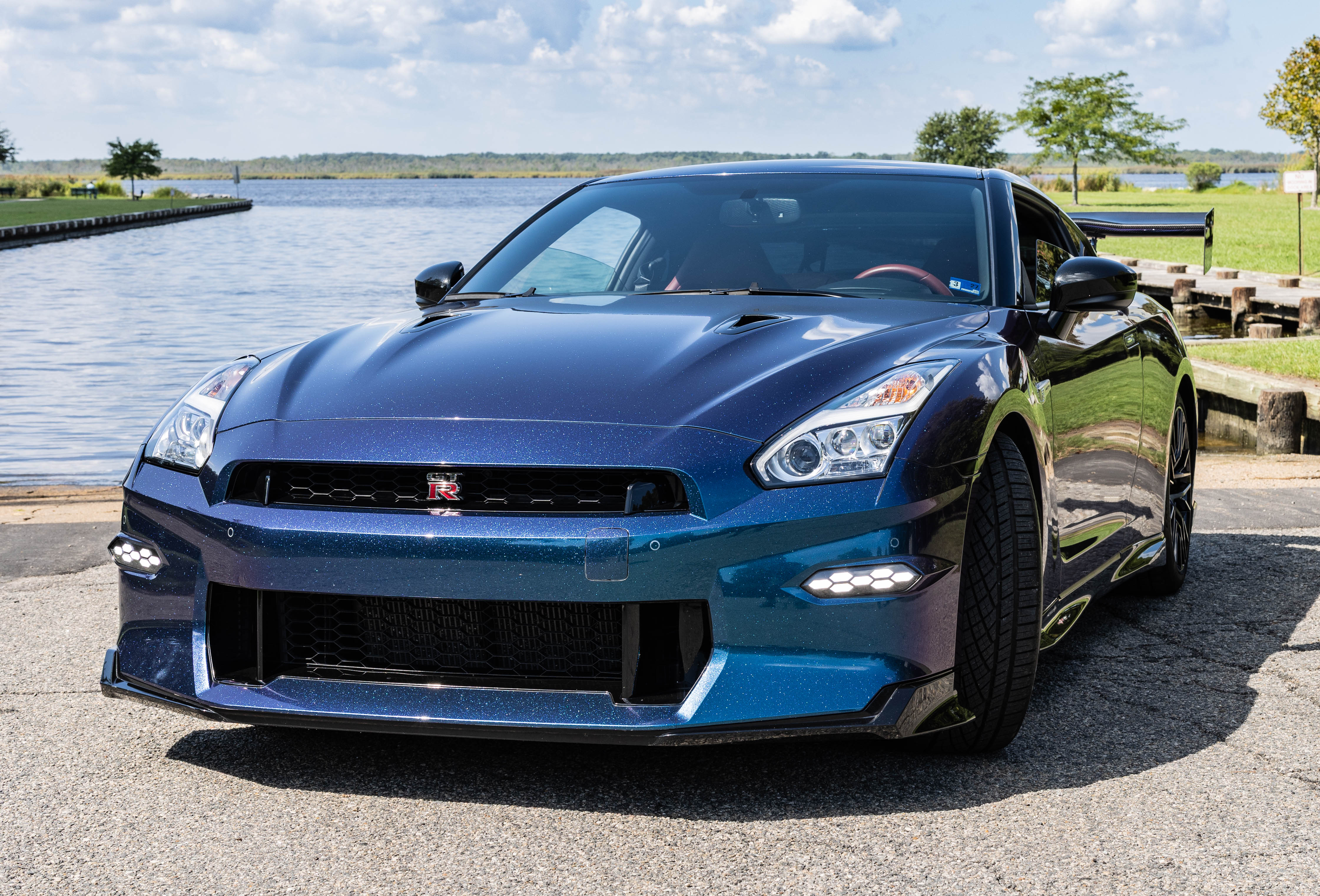 Head-on view of the 2024 Nissan GT-R Premium's GT-R grille and LED daytime running lights at the waterfront