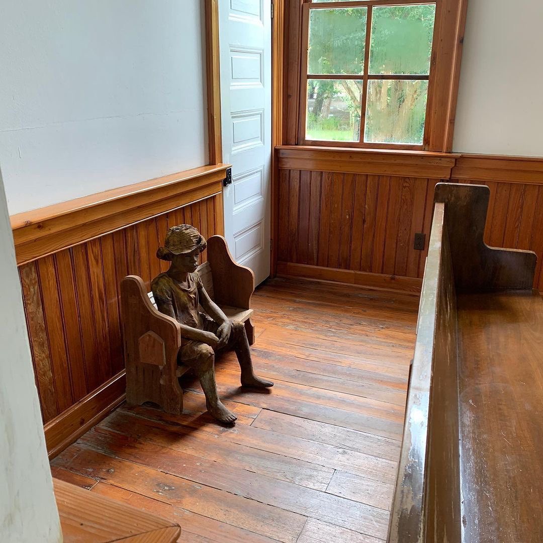 Sculpted child statue seated on a bench inside historic plantation chapel