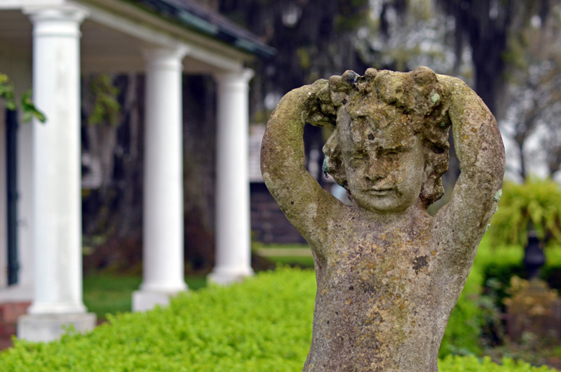 Weathered stone garden statue on the plantation lawn