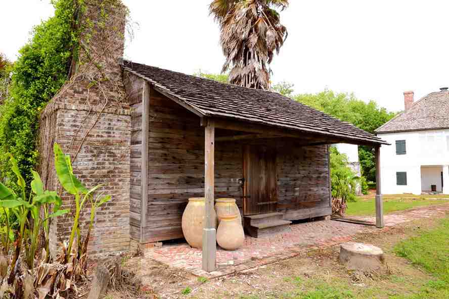 Rustic wooden outbuilding with clay urns near the plantation grounds