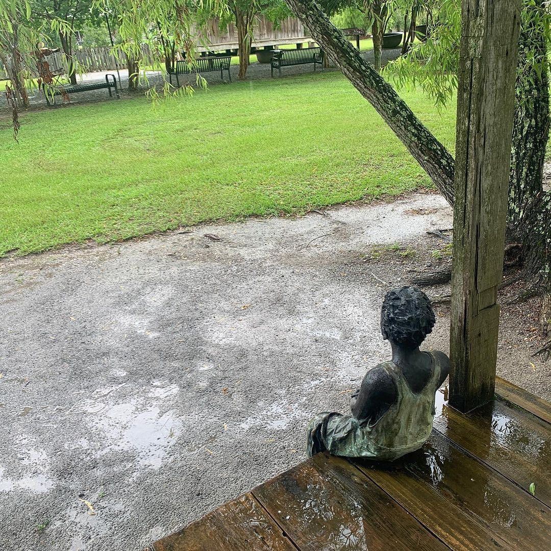 Sculpted bronze child statue sitting on porch looking towards plantation grounds