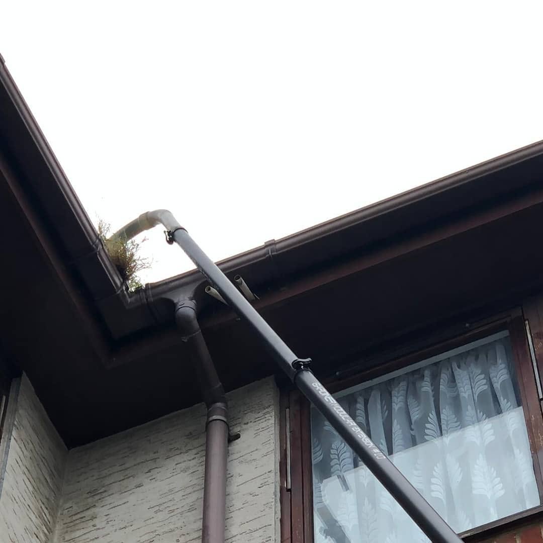 High-reach carbon fibre vacuum pole reaching a bungalow gutter from ground level