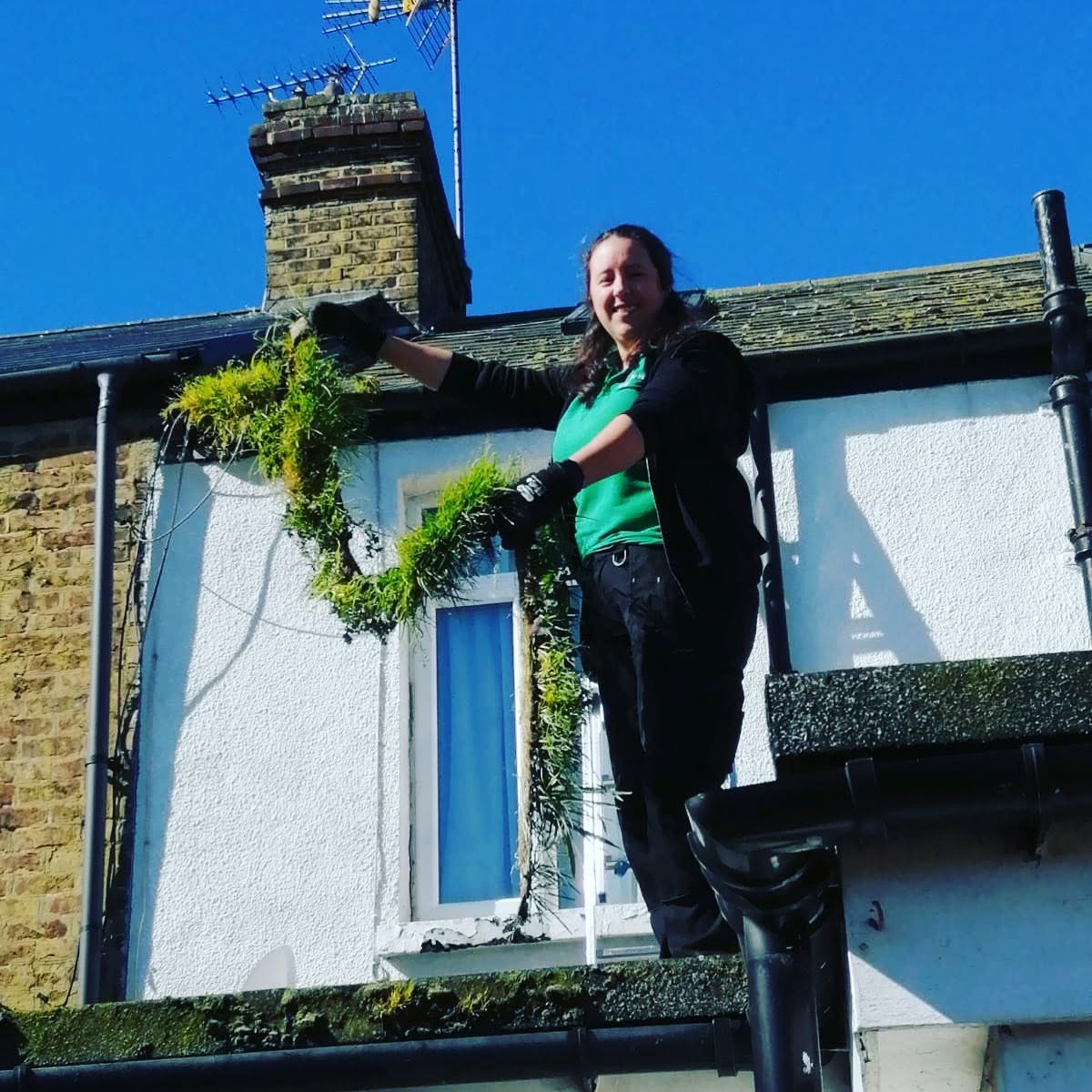 Julie, owner of Spring Clean Homes, clearing moss from a gutter