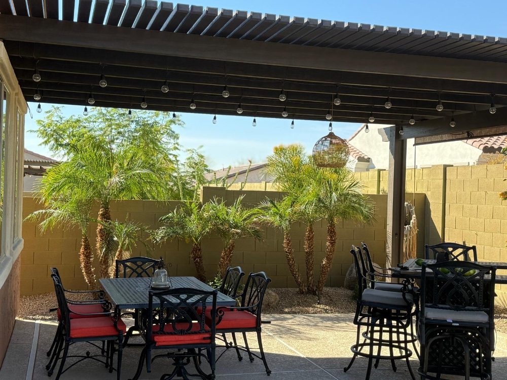Outdoor living area under a pergola with dining space and palm trees