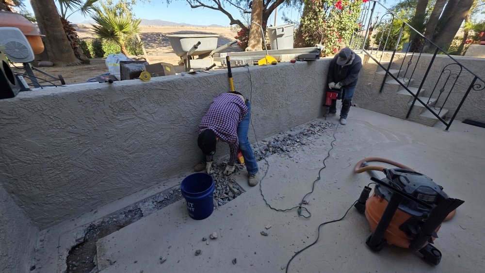 Before: Workers breaking concrete during a hardscaping renovation project