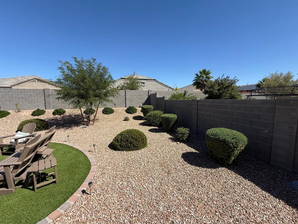 Backyard artificial turf installation with surrounding desert gravel and seating area