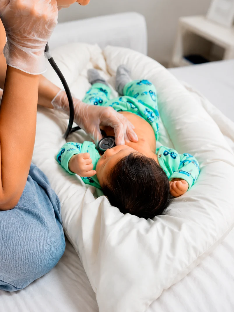 Fisioterapeuta auscultando bebê com estetoscópio durante atendimento domiciliar