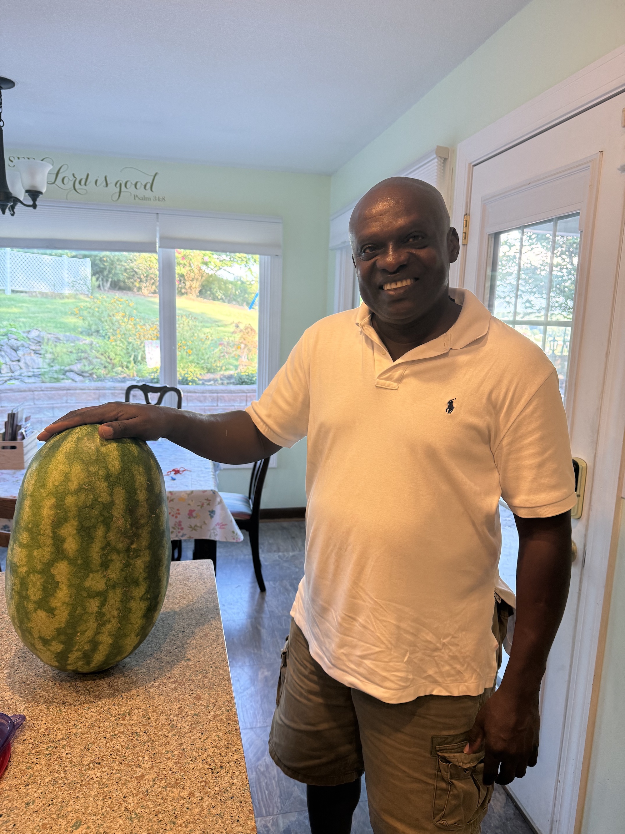 Deji Ayo with a watermelon grown in a Johnson City backyard garden, 16 inches long and 30.5 inches around