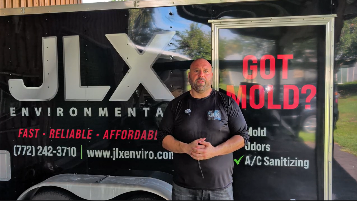 Devon Morante standing in front of the JLX Environmental trailer with company branding and phone number