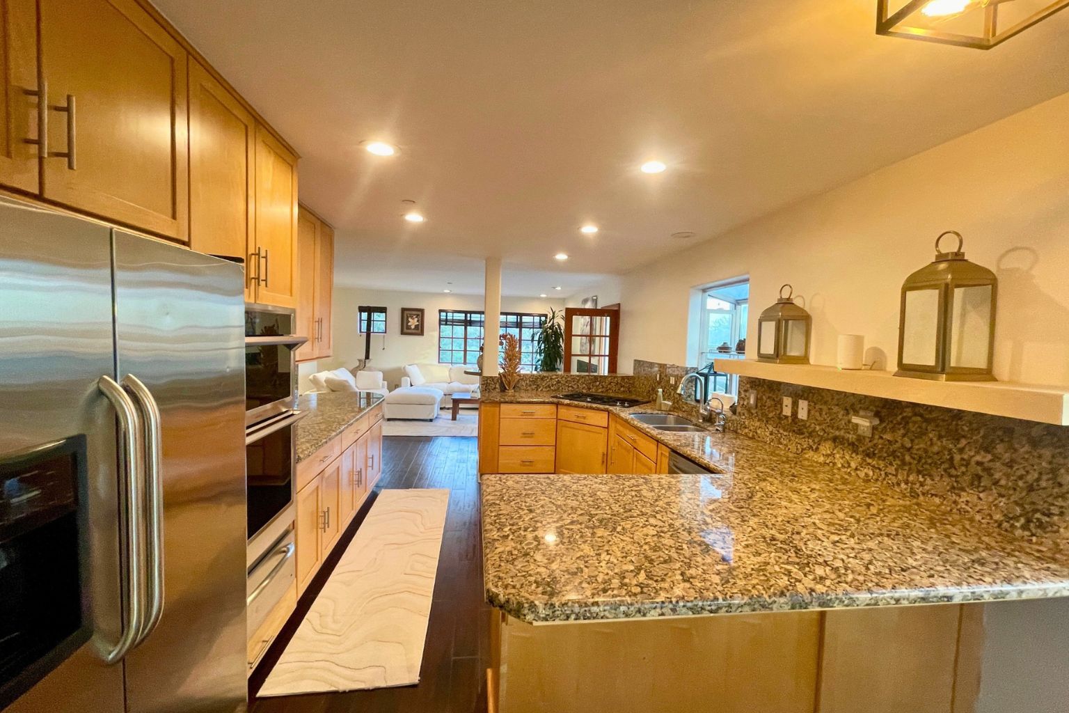 Chef's kitchen with granite countertops, custom cabinetry, stainless steel appliances, and an open view to the adjacent living area