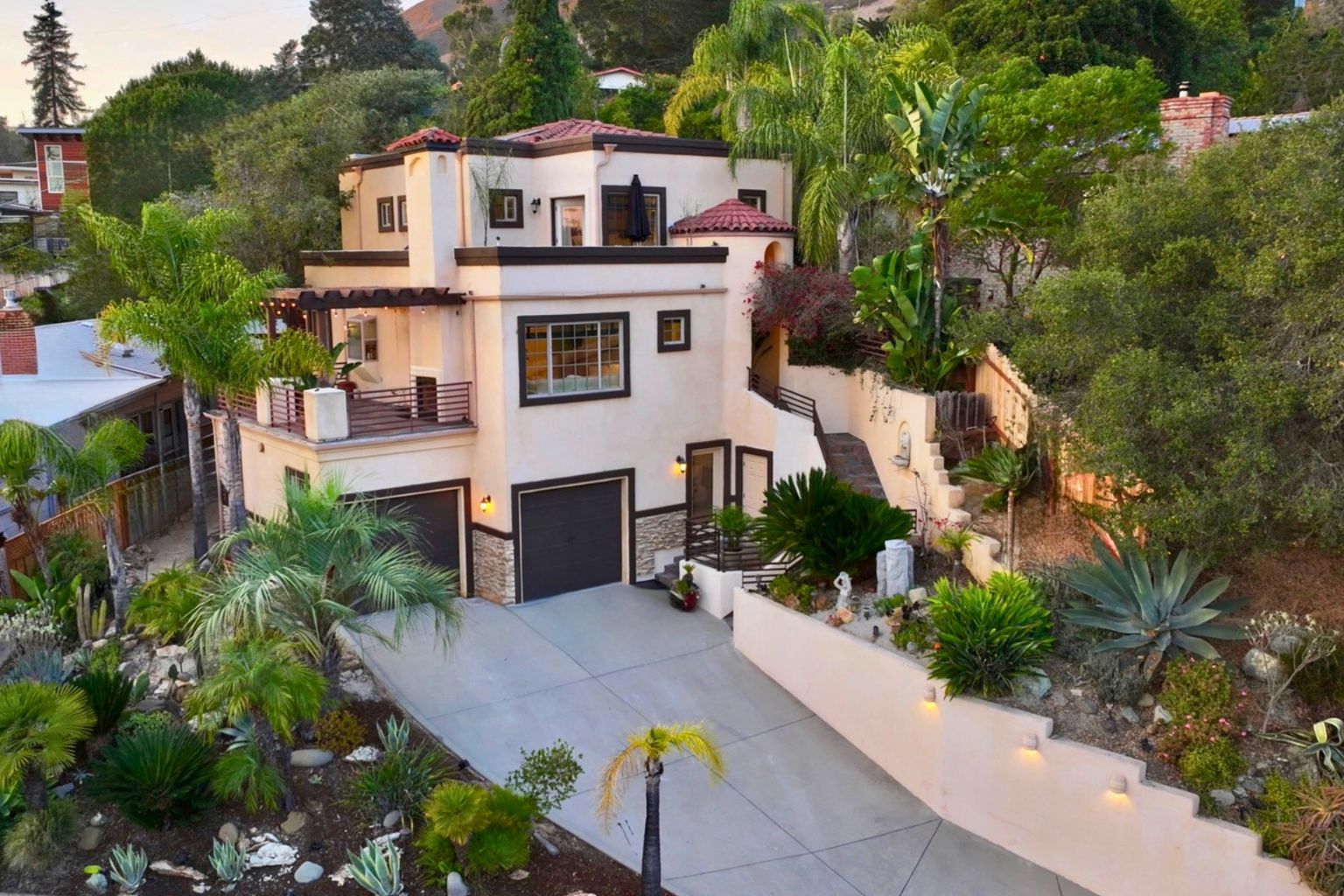 Aerial exterior view of 2176 Santa Ynez Avenue at dusk, showing the three-level Mediterranean architecture, rooftop terrace, and hillside landscaping