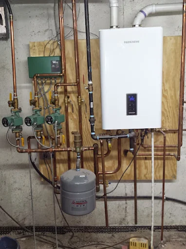Wall-mounted Navien high-efficiency tankless water heater boiler installation with copper manifold piping and circulator pumps in Alpharetta GA Wall-mounted Navien high-efficiency tankless water heater boiler installation with copper manifold piping and circulator pumps in Alpharetta GA