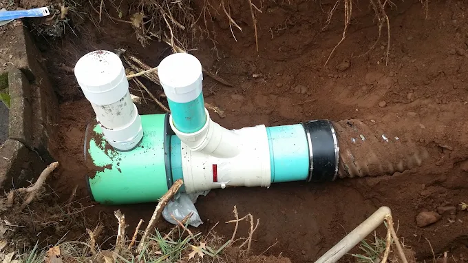Underground green SDR-35 sewer main line with Fernco flexible coupling transition and dual vertical PVC cleanout riser pipes in dirt trench Sandy Springs GA Underground green SDR-35 sewer main line with Fernco flexible coupling transition and dual vertical PVC cleanout riser pipes in dirt trench Sandy Springs GA