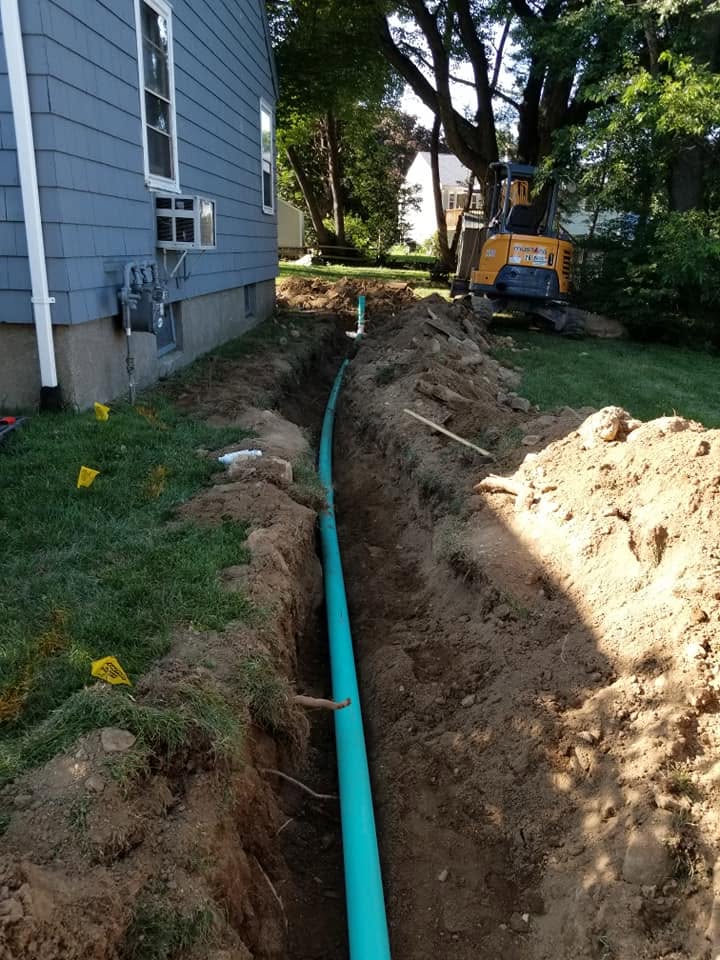 Heavy equipment excavator digging deep trench for long green SDR sewer main line replacement alongside residential house in Lawrenceville Metro Atlanta GA Heavy equipment excavator digging deep trench for long green SDR sewer main line replacement alongside residential house in Lawrenceville Metro Atlanta GA