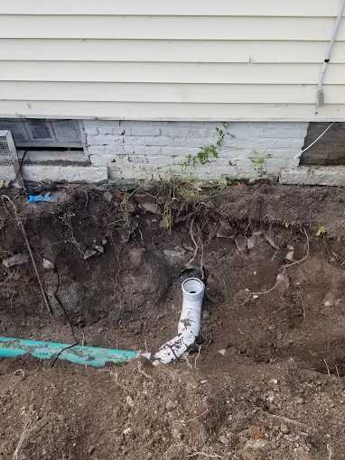 Excavated exterior foundation showing newly connected PVC sewer cleanout fitting and main line drain pipe in Marietta Atlanta GA Excavated exterior foundation showing newly connected PVC sewer cleanout fitting and main line drain pipe in Marietta Atlanta GA