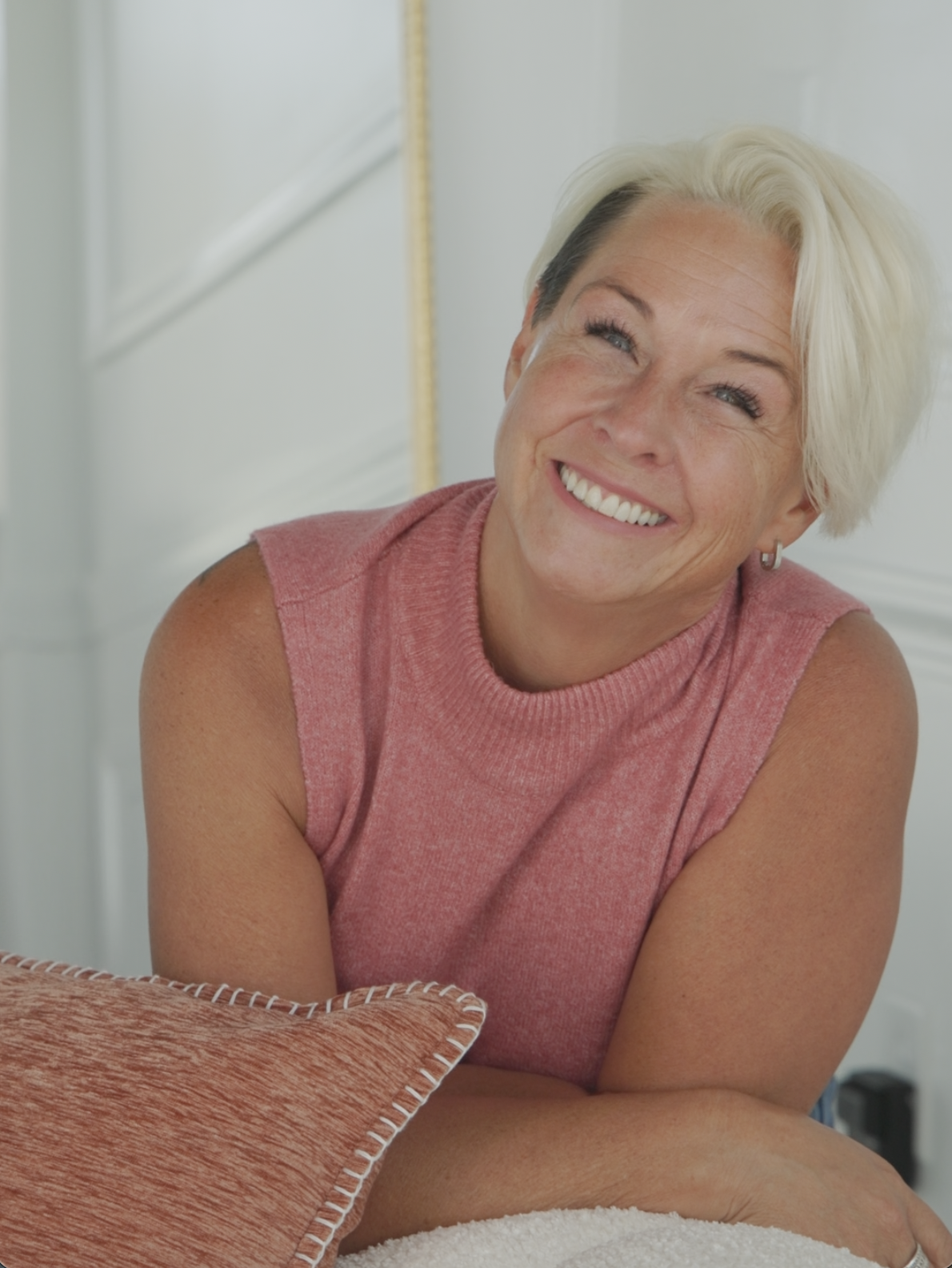 Lori smiling warmly in a sleeveless pink top, leaning forward