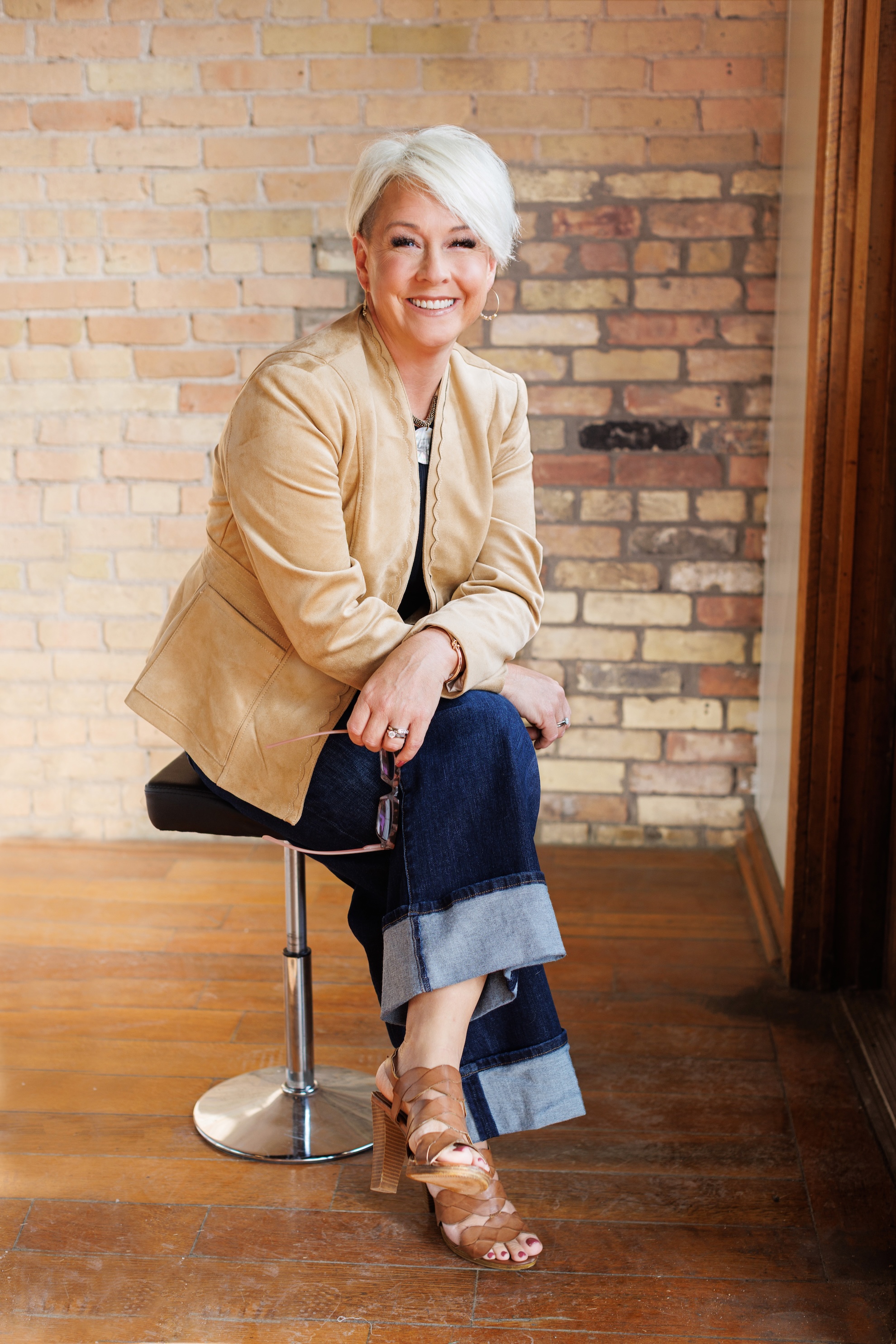 Lori Christophersen seated smiling in tan suede jacket
