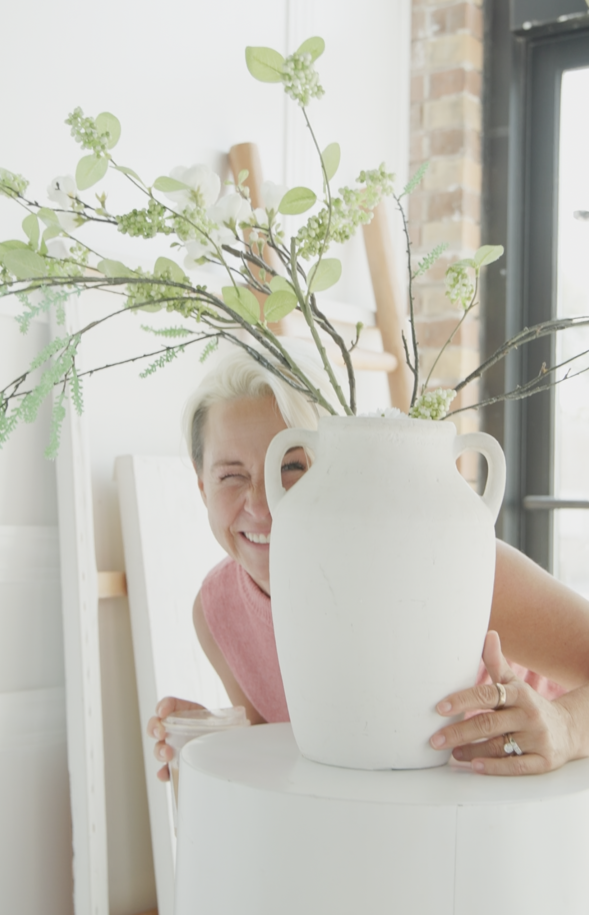 Lori peeking playfully from behind a vase
