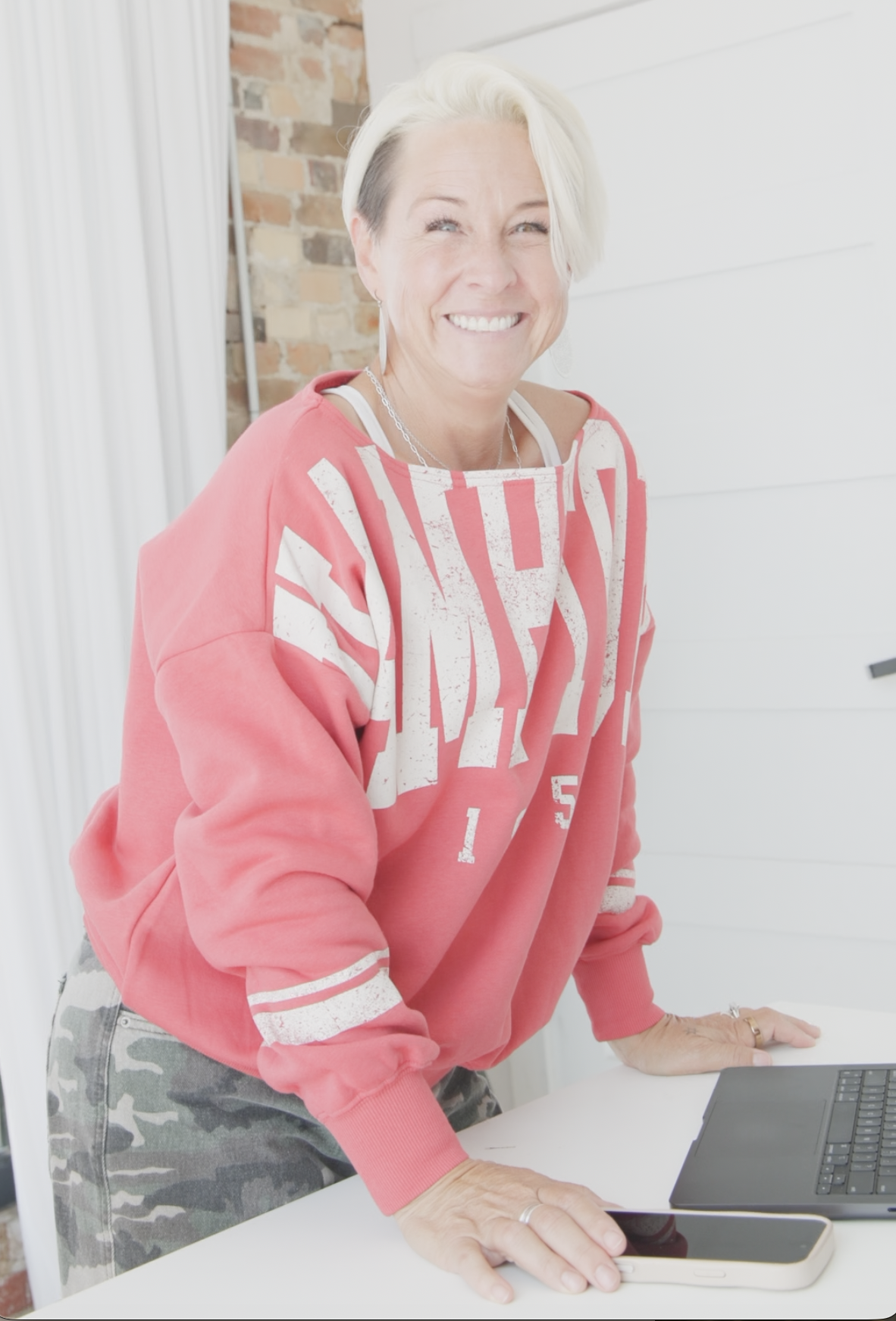 Lori Christophersen smiling at her desk with laptop and phone, ready to work together